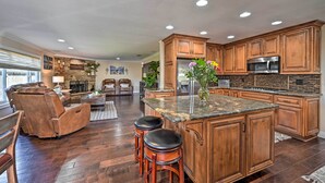A spacious kitchen with wooden cabinets, a granite countertop, and a built-in island with stools. - Vista Home w/ Pool ~ 11 Mi to Tamarack State Beach (Vista)