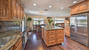A spacious kitchen with wooden cabinets, granite countertops, a stainless steel refrigerator, and a central island with drawers. - Vista Home w/ Pool ~ 11 Mi to Tamarack State Beach (Vista)