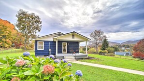 A two-story house with a porch, surrounded by a well-maintained lawn and flowering plants. - Home w/ Yard: 8 Mi to French Broad River Park (Asheville)