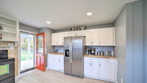 A modern kitchen with white cabinets, a stainless steel refrigerator, a coffee maker, and a stove. - Home w/ Yard: 8 Mi to French Broad River Park (Asheville)