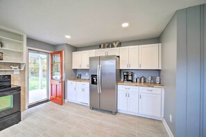 A modern kitchen with white cabinets, a stainless steel refrigerator, a coffee maker, and a stove. - Home w/ Yard: 8 Mi to French Broad River Park (Asheville)