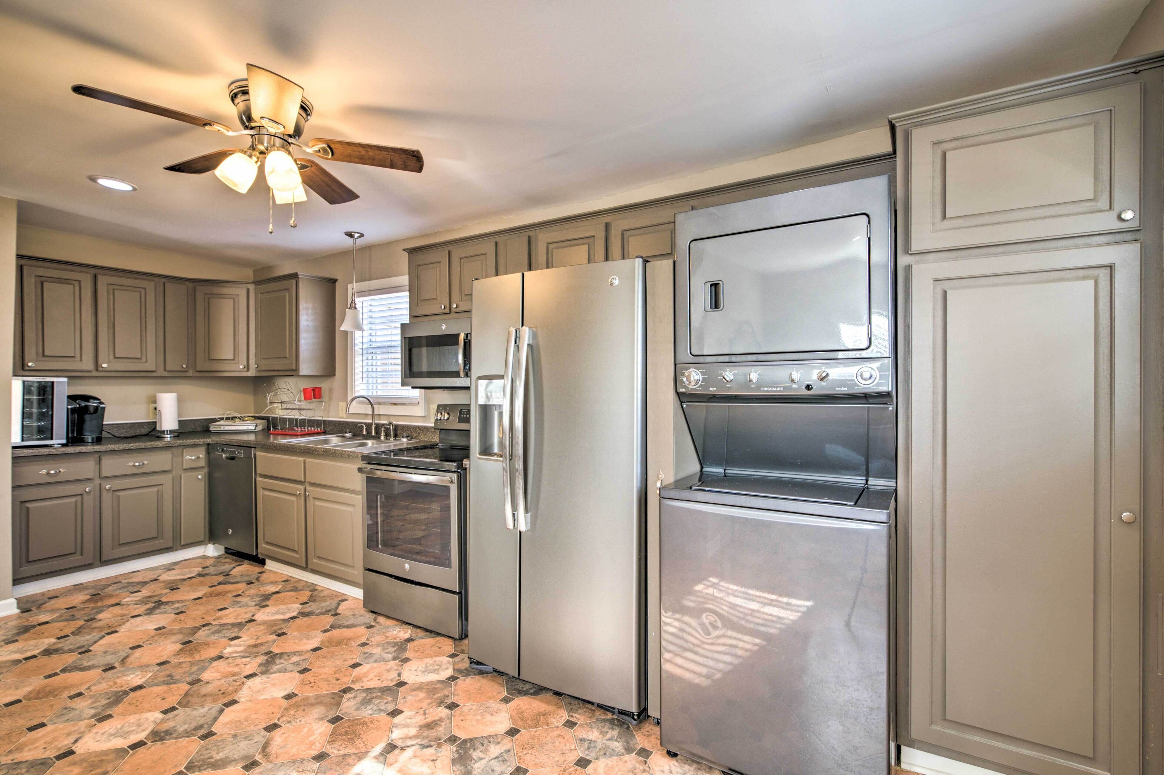 A modern kitchen with grey cabinets, stainless steel appliances, a built-in oven, microwave, and a ceiling fan.