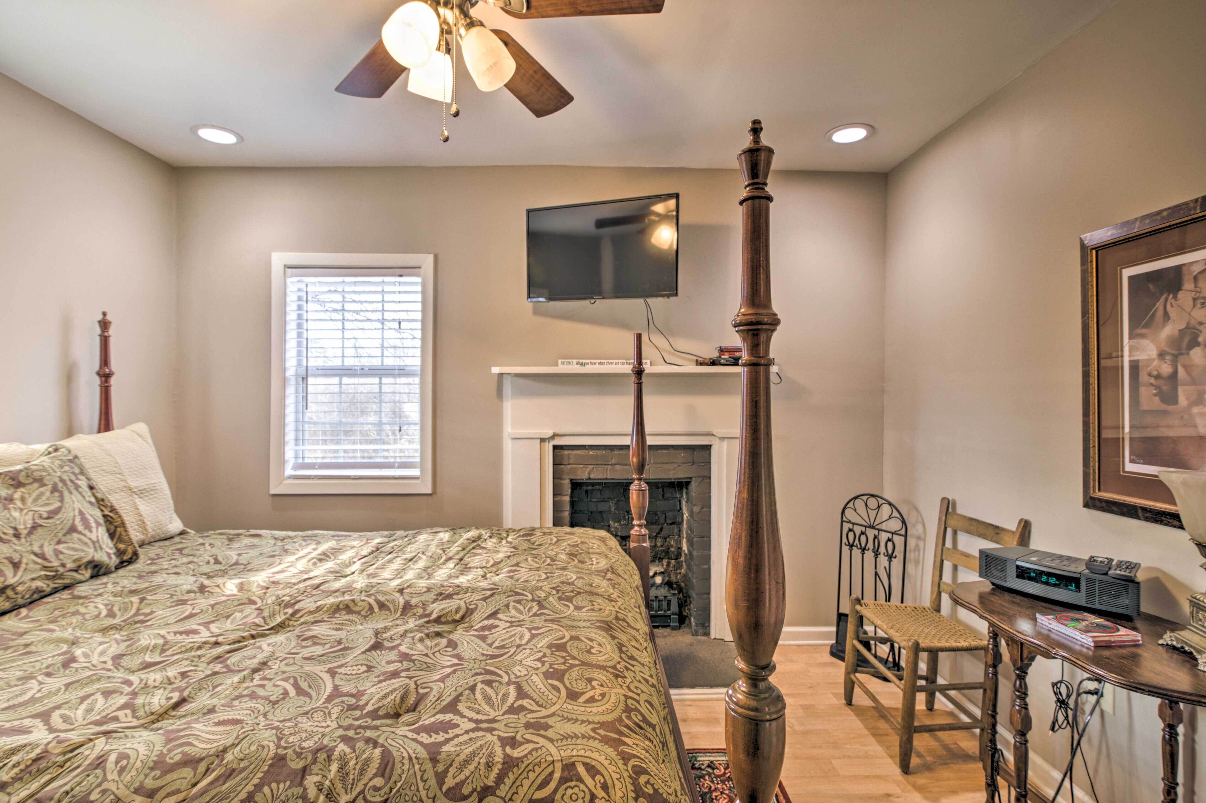 A bedroom with a bed, a fireplace, a television, and a dining table.