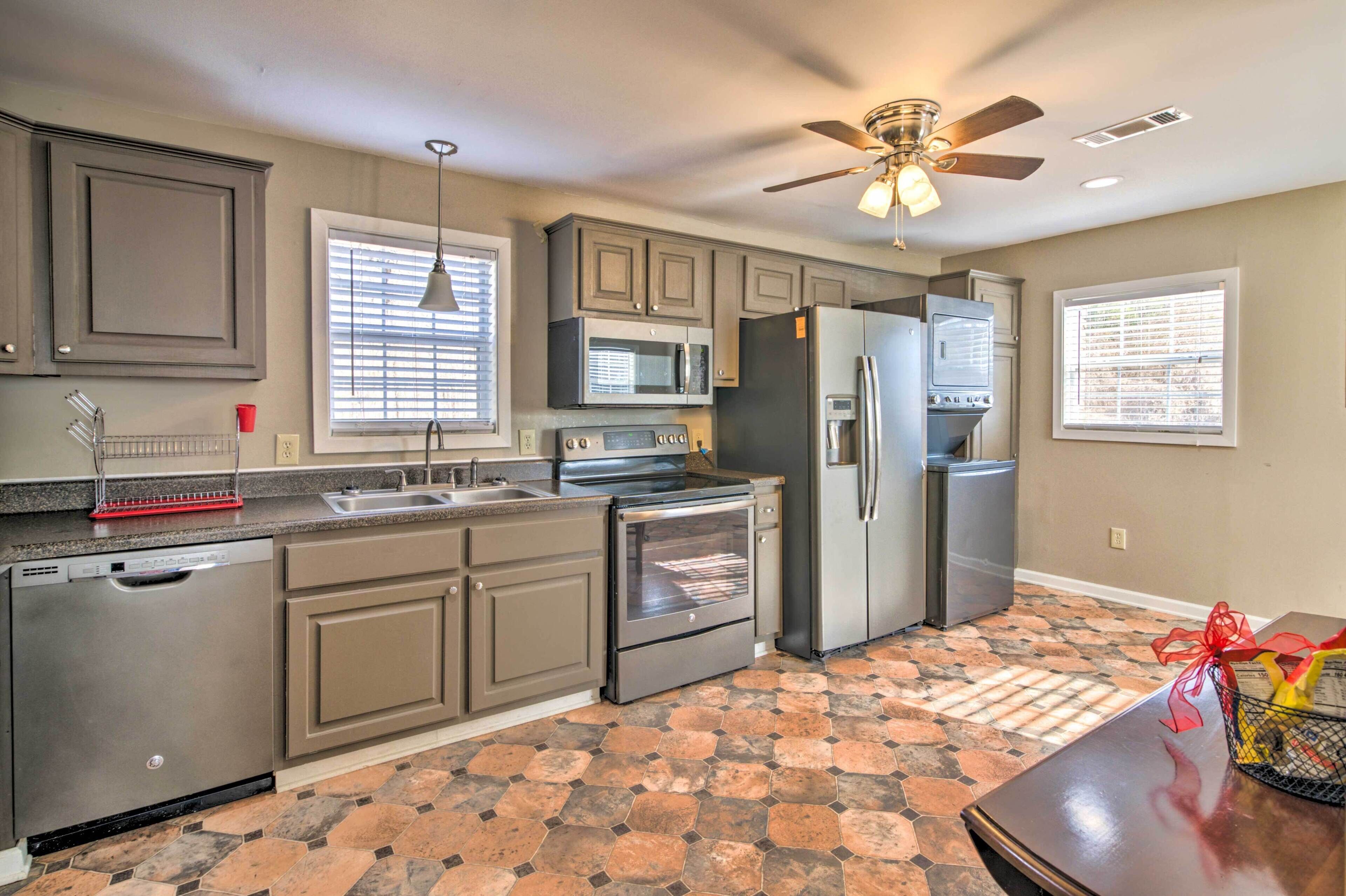 A modern kitchen with grey cabinets, stainless steel appliances, a dishwasher, and a tiled floor.