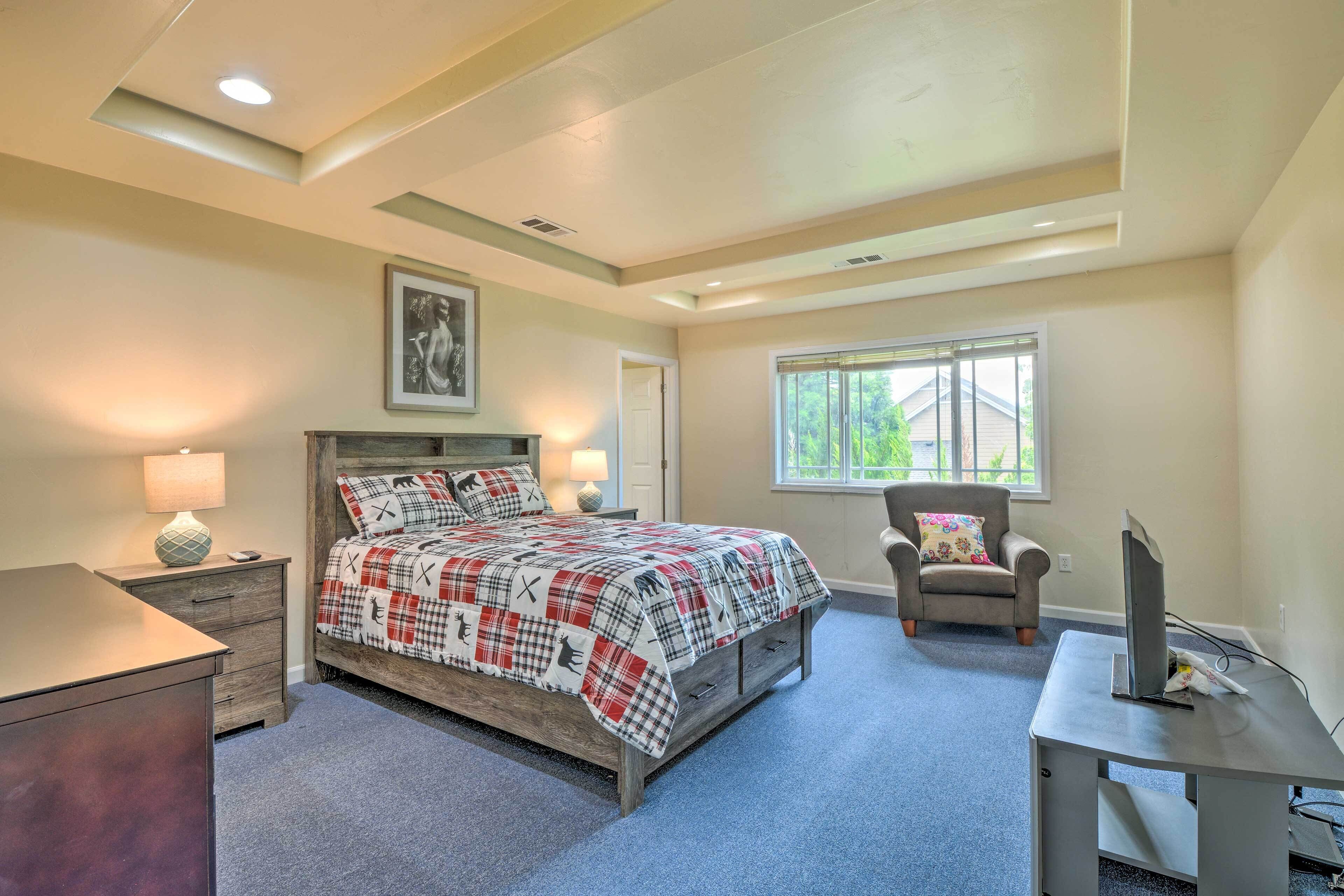 A bedroom with a bed, a desk, a chair, and a window.
