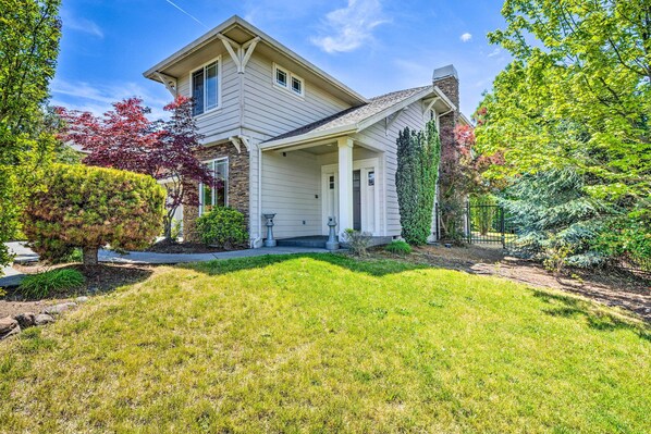 A two-story house with a covered porch, a stone chimney, and a well-maintained lawn.