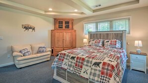 Un dormitorio con una cama grande, un armario de madera, un sofá y una ventana con persianas.