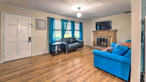 A living room with a blue sofa, a black leather couch, a wooden cabinet, and a fireplace. - Coastal Retreat! Harkers Island Boating Base (Harkers Island)