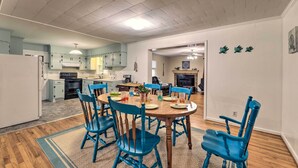 A dining area with a round table, blue chairs, and a kitchen in the background. - Coastal Retreat! Harkers Island Boating Base (Harkers Island)