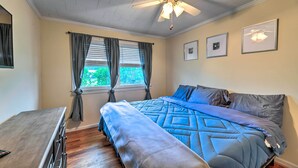 A bedroom with a bed, a desk, a ceiling fan, and a window with curtains. - Coastal Retreat! Harkers Island Boating Base (Harkers Island)