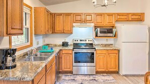 A kitchen with wooden cabinets, a stainless steel stove, a microwave, and a refrigerator.