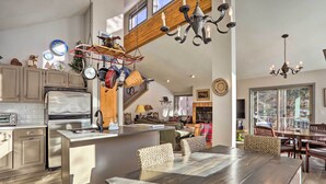 A spacious kitchen with modern appliances, a dining area with wooden furniture, and a loft bedroom with a large window. - Charming Mtn Home on Golf Course ~ 4 Mi to Slopes! (Avon)