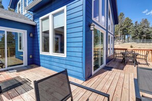 A blue house with a wooden deck, a sliding glass door, and a small outdoor table and chairs. - Colorado Cabin Getaway Near Pikes Peak! (Woodland Park)