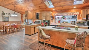 A spacious kitchen with wooden cabinets, a central island, and a dining area with wooden chairs.