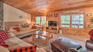 A cozy cabin interior with a wooden ceiling, stone wall, and a sign reading "FAITH FAMILY FRIENDS".