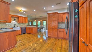 Una cocina amplia con armarios de madera, un refrigerador de acero inoxidable y una isla central.