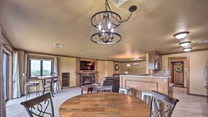A spacious dining area with a wooden table and chairs, a chandelier, and a kitchen in the background. - Golf Course & Lake Views: Cozy Afton Condo! (Afton)