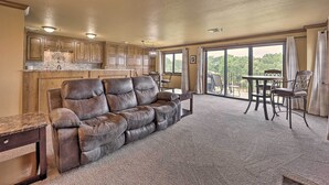 A spacious living area with a leather sofa, a dining table with chairs, and a kitchen with wooden cabinets. - Golf Course & Lake Views: Cozy Afton Condo! (Afton)