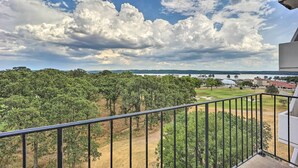 A balcony with a view of a golf course, trees, and a body of water in the distance. - Golf Course & Lake Views: Cozy Afton Condo! (Afton)