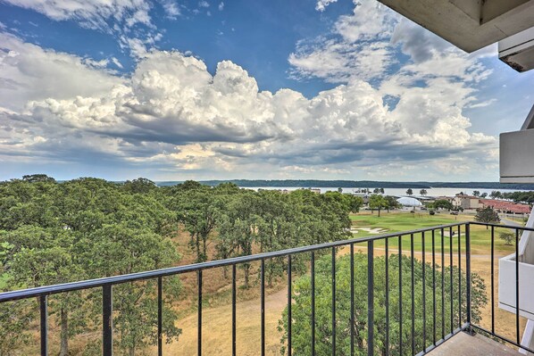 A balcony with a view of a golf course, trees, and a body of water in the distance. - Golf Course & Lake Views: Cozy Afton Condo! (Afton)