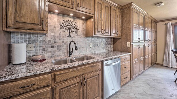 A kitchen with wooden cabinets, a granite countertop, a stainless steel sink, and a dishwasher. - Golf Course & Lake Views: Cozy Afton Condo! (Afton)