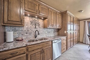A kitchen with wooden cabinets, a marble countertop, a stainless steel sink, and a built-in dishwasher. - Golf Course & Lake Views: Cozy Afton Condo! (Afton)