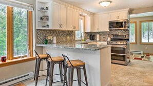 A modern kitchen with white cabinets, a granite countertop, and a large island with bar stools.