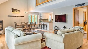 A spacious living room with a high ceiling, a dining area, and a kitchen.