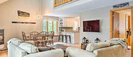 A spacious living room with a high ceiling, a dining area, and a kitchen.