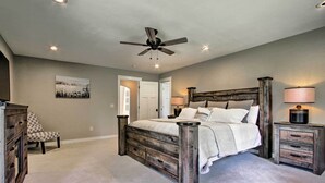 A bedroom with a wooden bed frame, a ceiling fan, and a nightstand with a lamp. - Creekfront Lincoln Home, Steps From Downtown! (Lincoln)