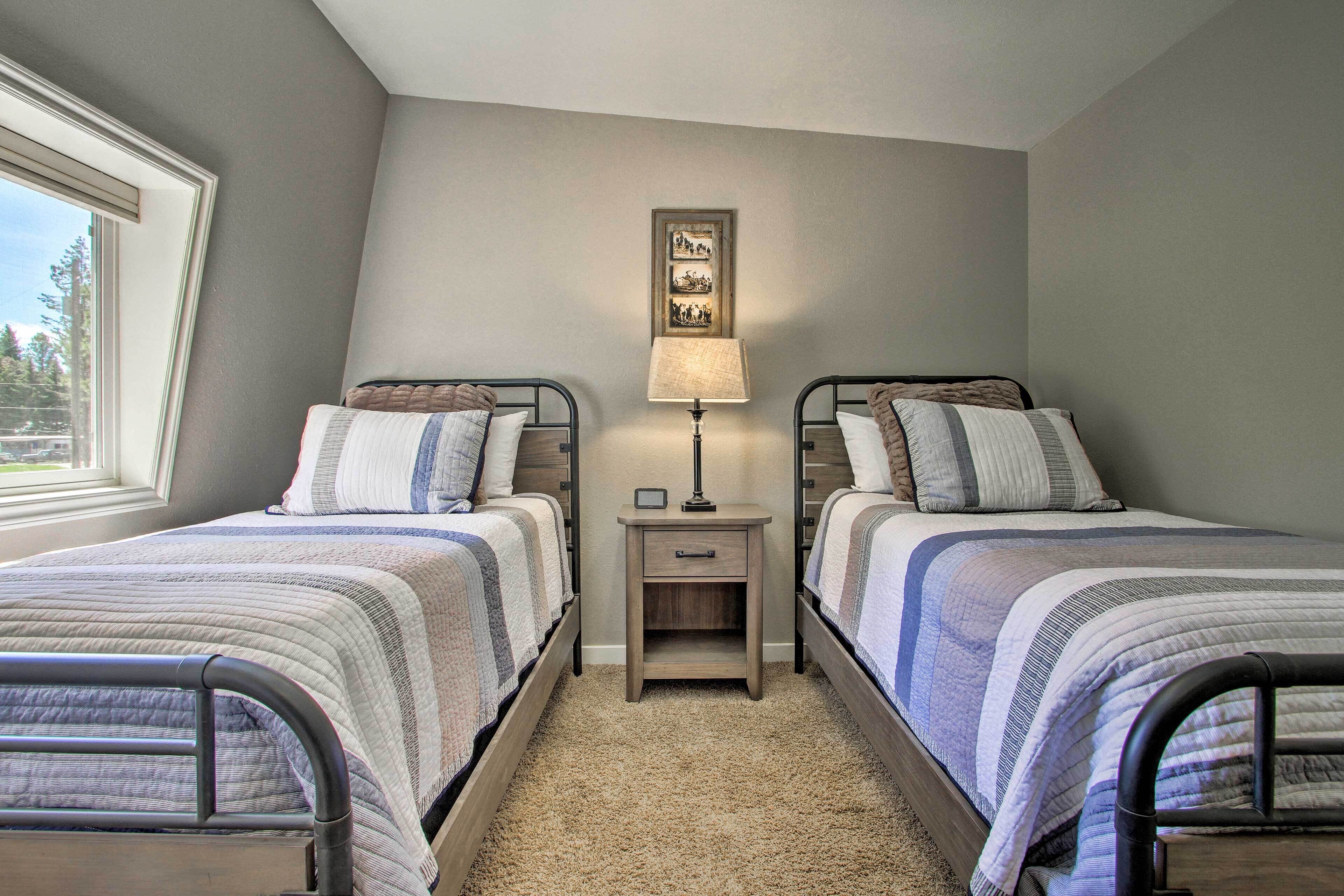 A bedroom with two twin beds, a nightstand with a lamp, and a framed picture on the wall.