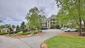 A residential driveway with two cars parked, a house with a green roof, and a gazebo in the background.