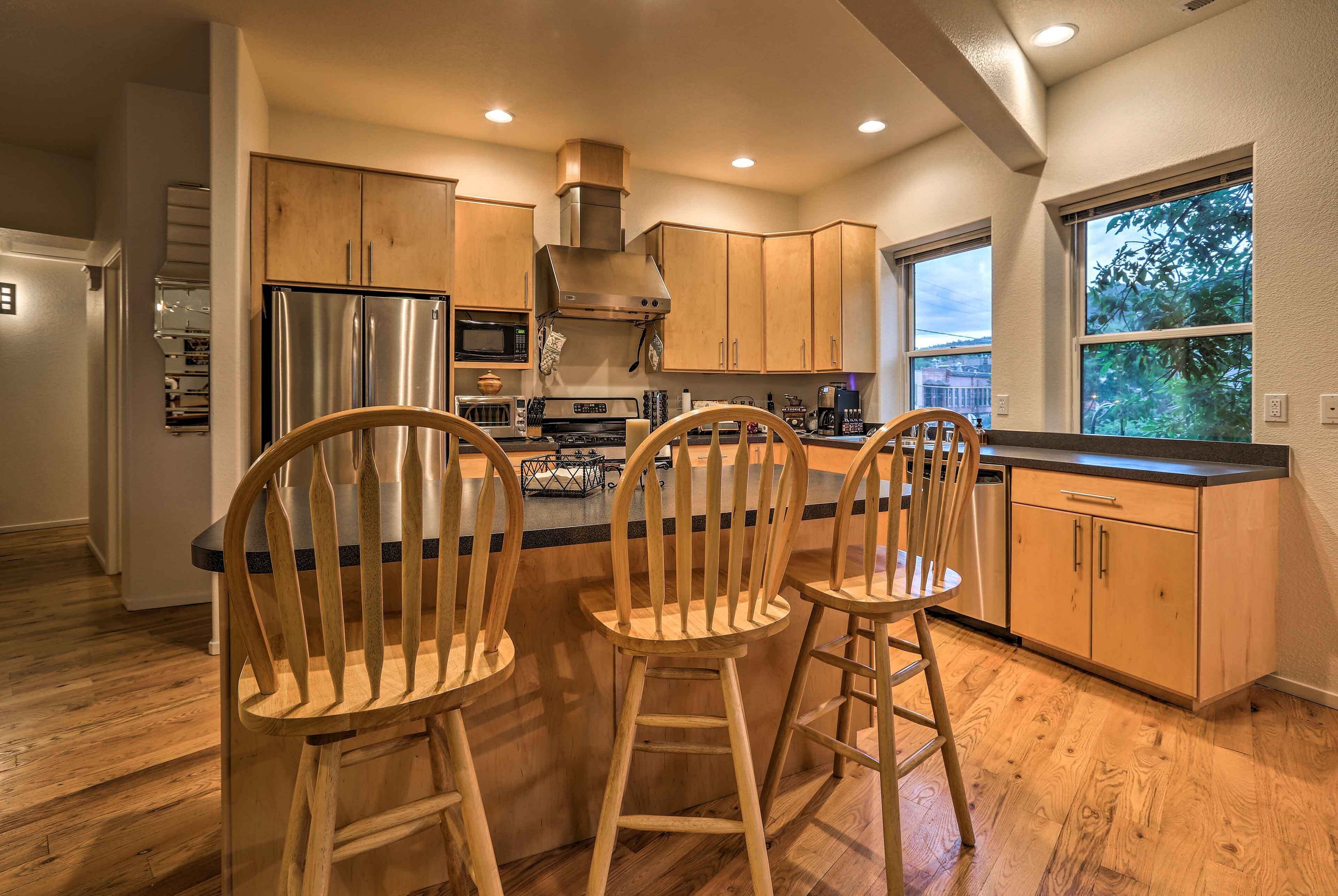 A modern kitchen with wooden cabinets, stainless steel appliances, and a large island with bar stools.