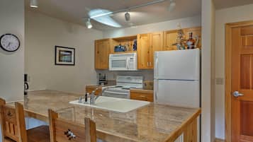 A compact kitchen with wooden cabinets, a white refrigerator, a microwave, and a sink.