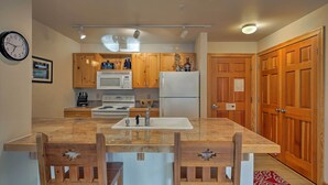 Eine Küche mit Holzausstattung, einer Mikrowelle, einem Kühlschrank und einem Spülbecken.