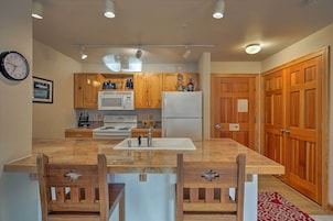 A kitchen with wooden cabinets, a microwave, a refrigerator, and a sink.