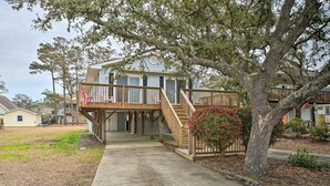 A two-story house with a wooden deck and a staircase leading to the entrance. - Cozy Oak Island House < 1 Mi to Beaches! (Oak Island)