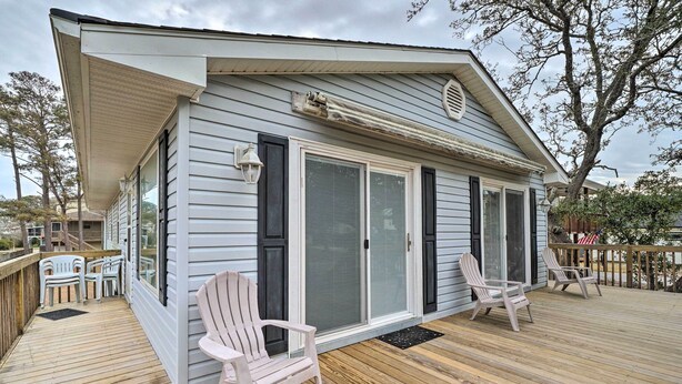 A house with a covered porch, sliding glass doors, and outdoor seating. - Cozy Oak Island House < 1 Mi to Beaches! (Oak Island)