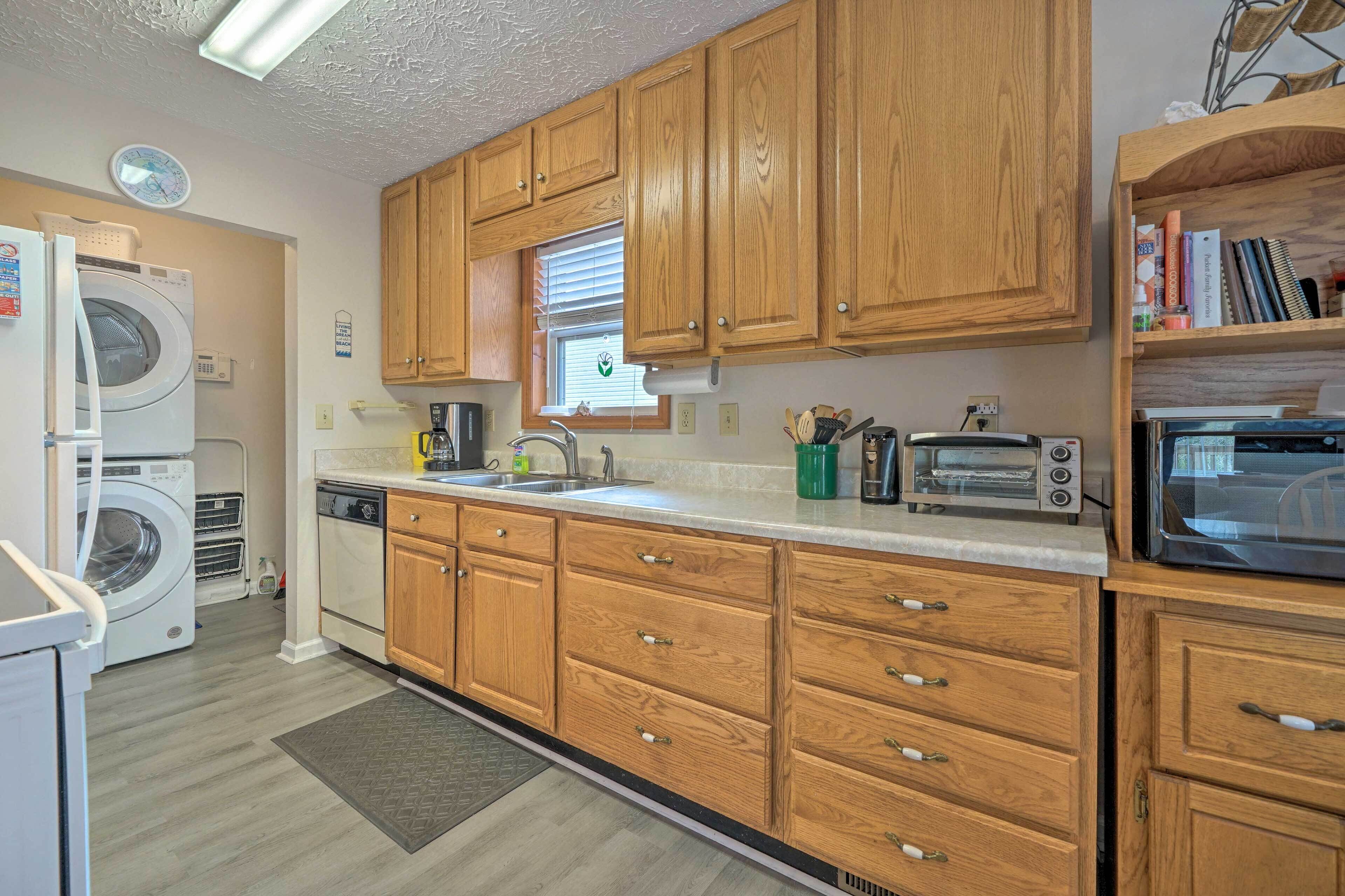 A compact kitchen with wooden cabinets, a built-in oven, a microwave, and a washing machine.