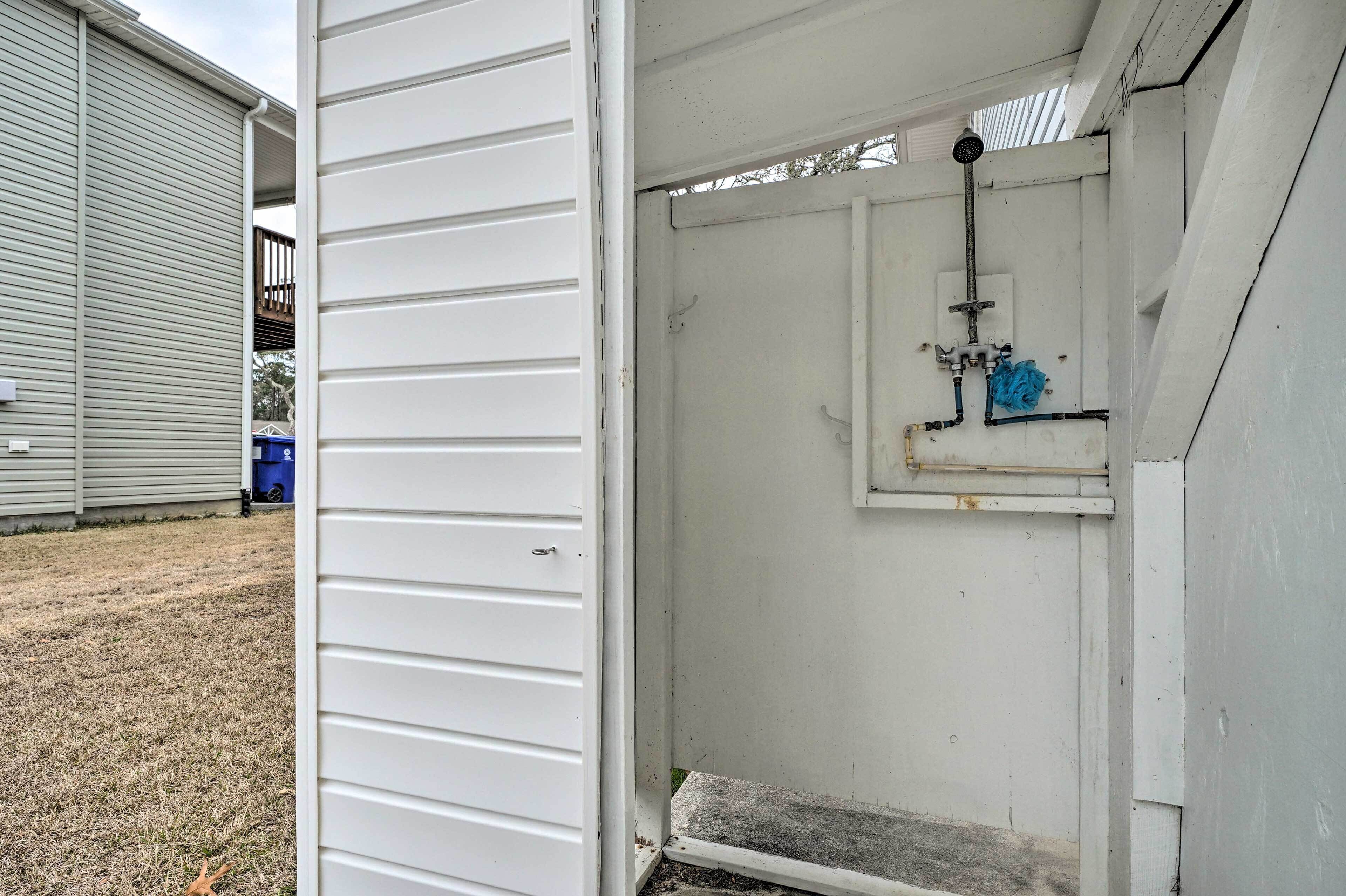 Ein kleiner, abgeschlossener Hauswirtschaftsraum mit Dusche, einer Metalttür und einem Betontritt, der zu einer Garage führt.