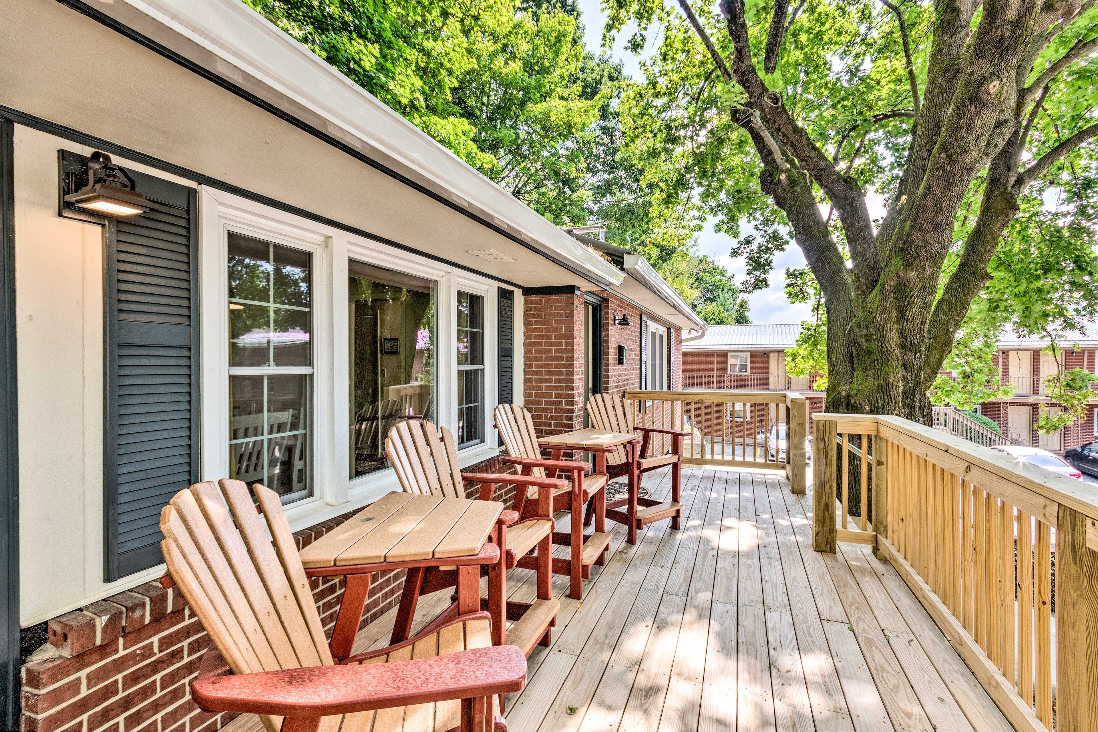 A wooden deck with outdoor seating and a brick building.