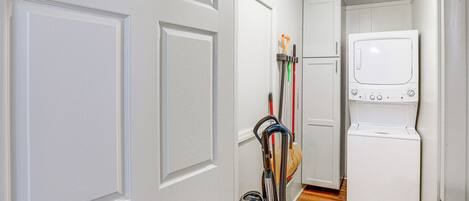 A laundry room with a washing machine and a clothes drying rack.