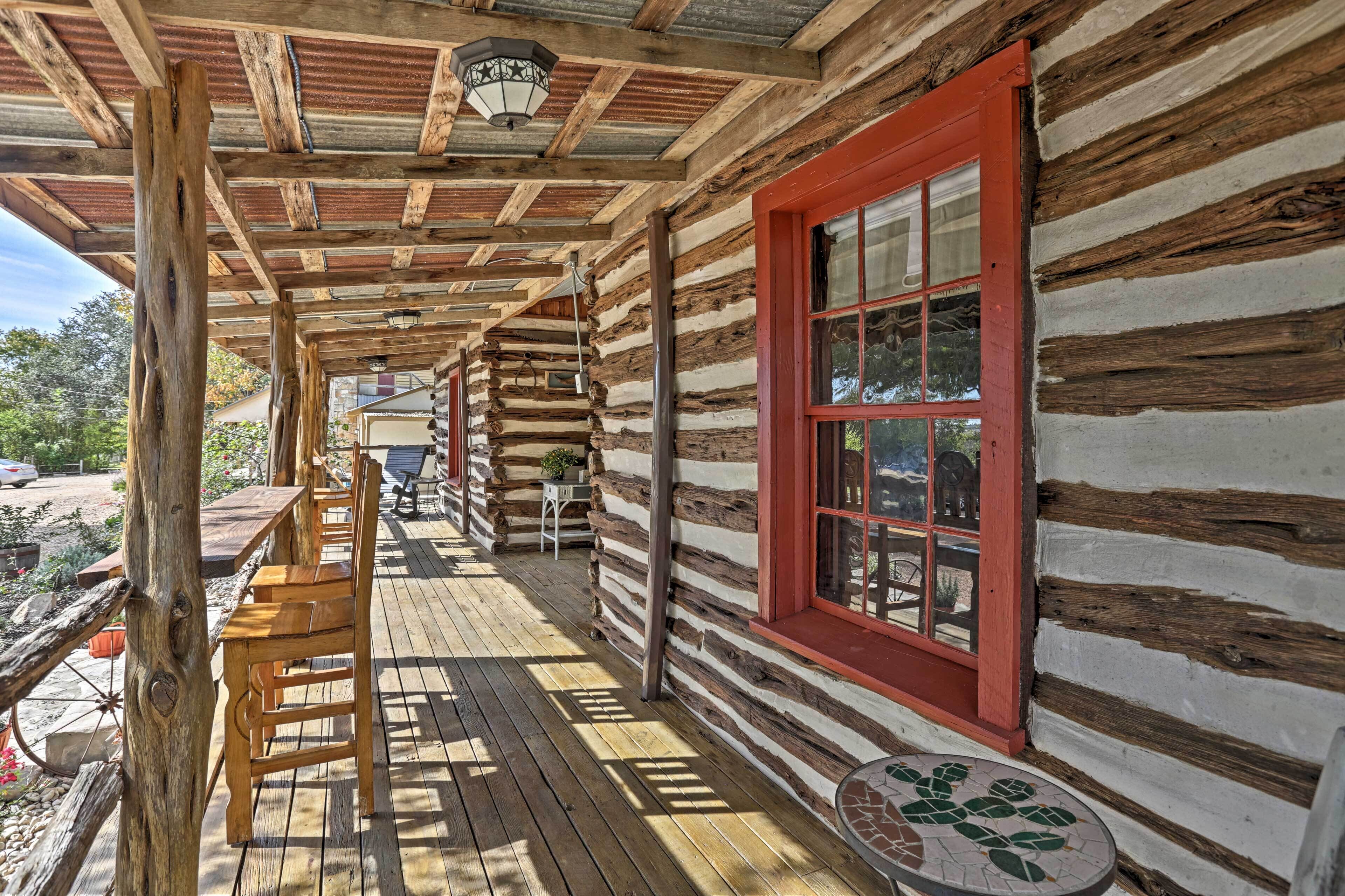 A log cabin with a wooden deck, a red-framed window, and a lantern hanging from the ceiling.