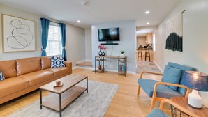 A modern living room with a sofa, coffee table, and a TV mounted on the wall.