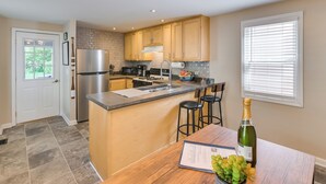 A modern kitchen with a central island, stainless steel appliances, and a dining area with a wooden table and chairs.