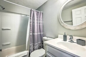 A bathroom with a shower, toilet, sink, and a mirror.