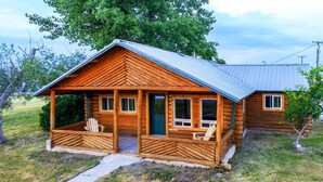 A log cabin with a porch, two windows, and a door.