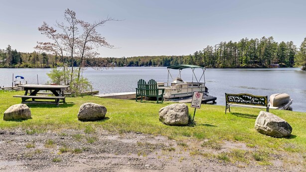 Un espace de pique-nique au bord du lac, équipé d’un banc, d’une table de pique-nique et d’un bateau amarré à proximité.