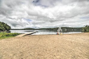 A beach with a lifeguard tower, a dock, and a calm lake surrounded by hills. - Pet-friendly Saranac Lake Retreat w/ Deck & Yard (Saranac Lake)