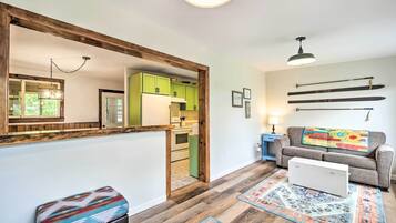 A modern kitchen with green cabinets, a white refrigerator, and a wooden bench.